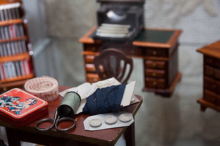 selective focus photo of green silk thread spool beside measuring tape and red Betty Boop case thumbnail