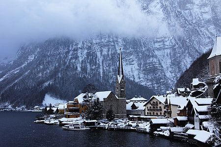 village beside snow cap mountain and body of water thumbnail