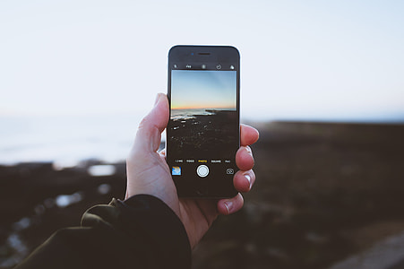 person taking photo of sea during golden hour thumbnail