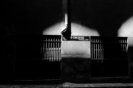 grayscale photography of gate beside no smoking signage attached on wall thumbnail