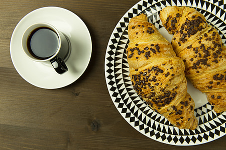 Overhead shot of coffee cup and croissants on a wood table thumbnail
