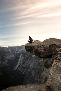 person sitting on gray rock formation thumbnail
