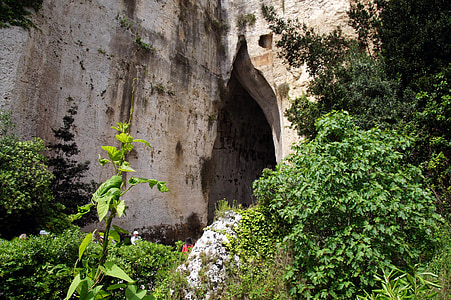 gray cave covered in green trees thumbnail