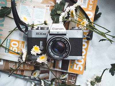 gray and black Canon Exee SLR camera beside white petaled flowers thumbnail