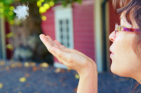 shallow focus photography of woman blowing dandelion on her palm thumbnail