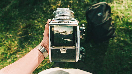 person holding SLR camera showing mountain range thumbnail
