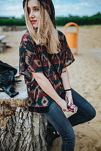 Beautiful blonde woman relaxing with a can of coke on a tree stump by the beach thumbnail