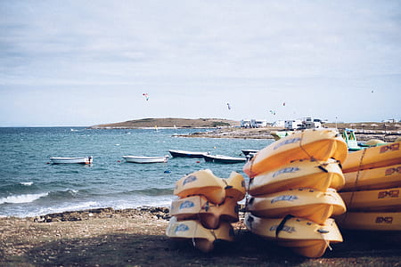 yellow kayak on sand near ocean during daytime thumbnail