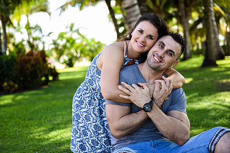 man wearing gray t-shirt behind hugging woman wearing blue and white floral sleeveless dress during daytime thumbnail