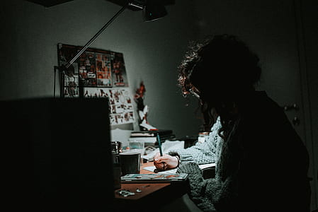 silhouette photo of person writing on desk with study lamp thumbnail