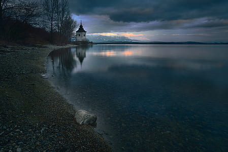 white lighthouse near calm body of water photo thumbnail