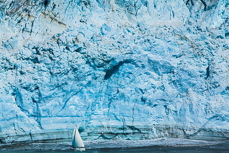 white sailboat beside blue rock formation during daytime thumbnail