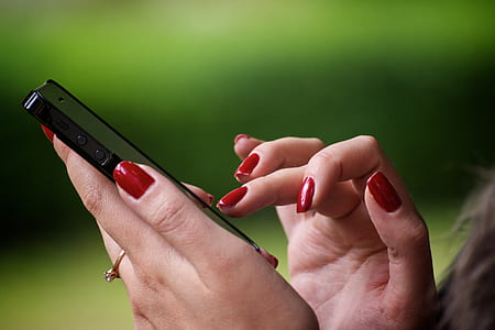 woman with red manicure using black iPhone 5 thumbnail