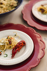 Fancy dinner with seafood pasta, crayfish and red wine by the table decorated with roses thumbnail