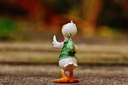 white and green duck figurine on brown surface thumbnail