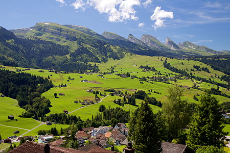 village surrounded with plain fields and mountains during daytime thumbnail