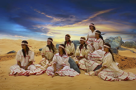 group of women wearing white dress sitting on brown sand thumbnail