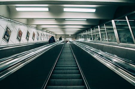empty escalator beside two people standing beside railings inside room with lights turned on thumbnail