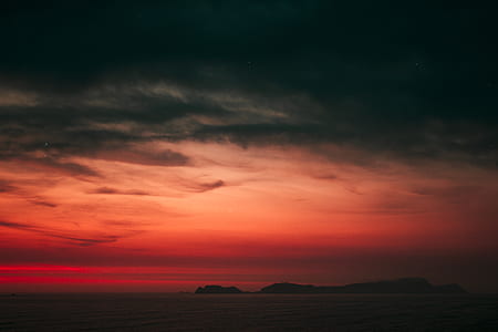 silhouette of mountain under orange sky thumbnail