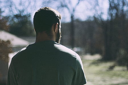 man in grey T-shirt standing facing trees thumbnail
