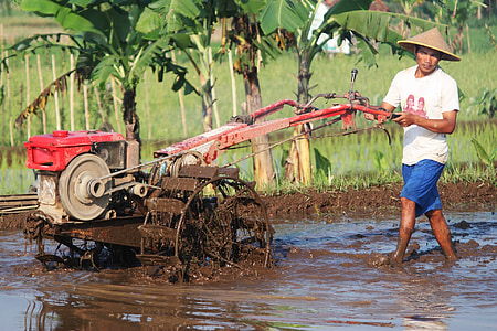 man using farming machine on wet field during daytime thumbnail