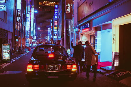 two man beside car staring up on building during nighttime thumbnail