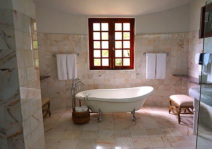 white bathtub inside beige tiled bathroom thumbnail