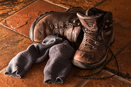 pair of brown leather boots and gray socks on brown tiles thumbnail