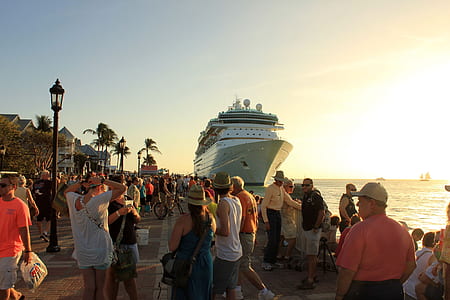 group of people on shore near cruise ship thumbnail