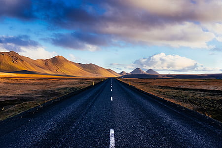 pathway leading to mountain ranges surrounded by grass field thumbnail