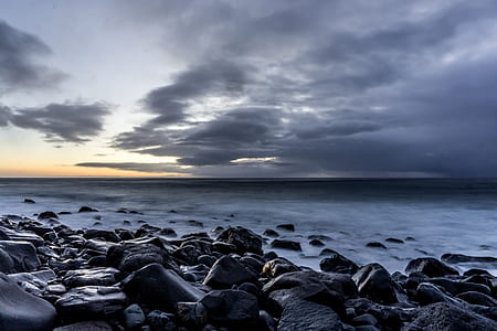 landscape photography of sea with rock formations under nimbus clouds thumbnail
