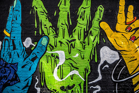 Street art depicting vibrantly coloured hands captured on a brick wall thumbnail