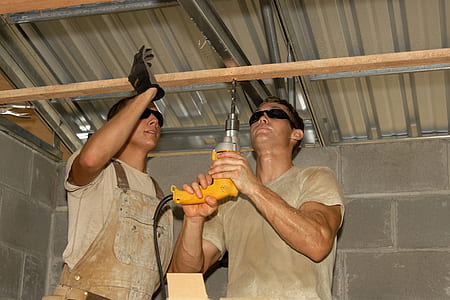 man wearing gray crew-neck t-shirt using yellow corded hand drill thumbnail