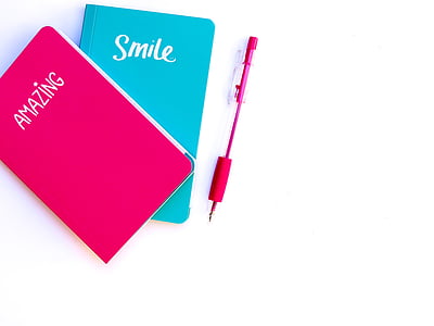 two teal and pink books with pink click pen thumbnail