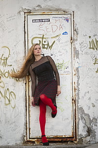 woman leaning on white metal door while rising her left leg during daytime thumbnail