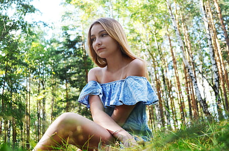woman wearing blue and white strapless top sitting on green grasses thumbnail