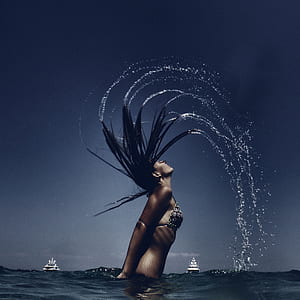 woman in body of water splashing water with hair thumbnail