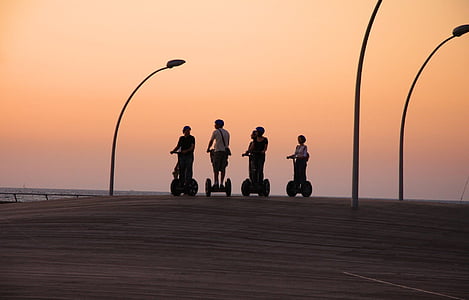 four person riding personal transporter during golden hour thumbnail