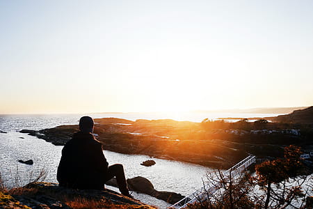 Silhouette Photo of Person Sitting Near Cliff during Golden Hour thumbnail