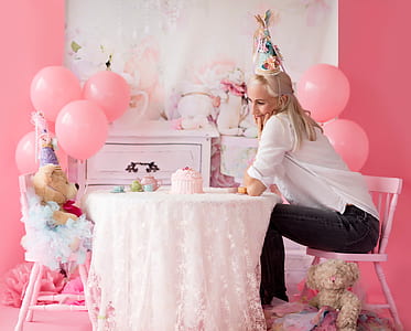 woman wearing party hat sitting on chair by the table with teddy bear in front of her thumbnail