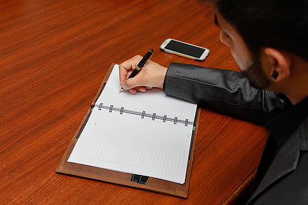 person writing on white planner thumbnail