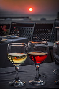 two clear wine glasses filled with red and yellow liquids thumbnail