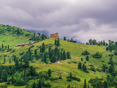 brown painted house on top of hill surrounded with trees under white cloudy skies at daytime thumbnail