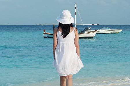 woman wearing white spaghetti strap dress standing by the beach thumbnail