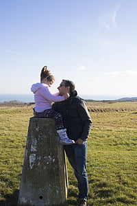 girl sitting on stone in front of man standing thumbnail