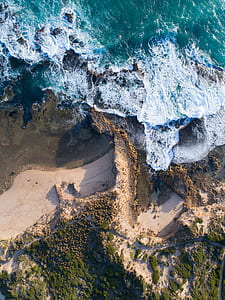 bird's eye view of body of water crashing on rocks thumbnail