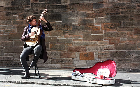man wearing brown leather coat with black denim jeans playing natural finish classical guitar thumbnail