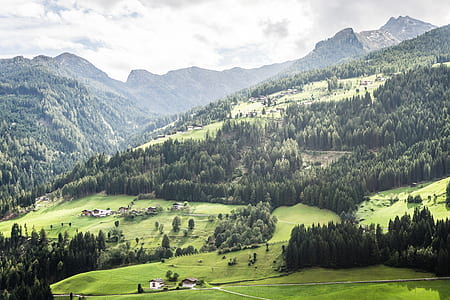 aerial photo of green grass field and mountain under gray sky during daytime thumbnail
