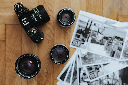Old Zenit camera and a Canon camera with black-and-white photos on a wooden table thumbnail