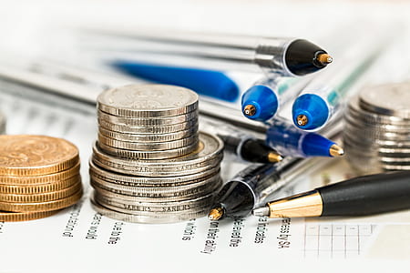 stack of silver-colored and gold-colored coins near blue and black ballpoint pens thumbnail